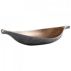 a large metal bowl sitting on top of a white wall next to a wooden spoon