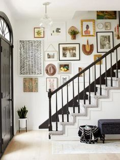 an entryway with stairs and pictures on the wall, along with a black door