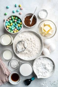 the ingredients for an easter cake laid out on a white surface with eggs, flour, butter, and chocolate