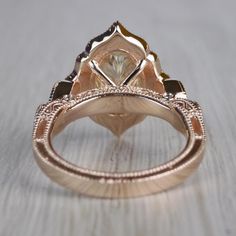 a close up view of a fancy ring on a wooden surface with the center stone surrounded by smaller stones