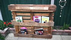 a wooden bench with books on it sitting in front of a building