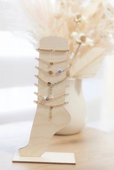 a white vase filled with lots of jewelry on top of a wooden table next to a plant