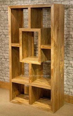 a wooden bookcase sitting in front of a brick wall