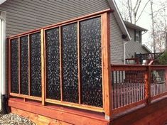 a wooden deck with an iron screen on the top and side of it in front of a house