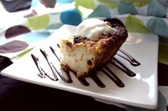 a piece of cake on a white plate with chocolate sauce and whipped cream drizzled over it