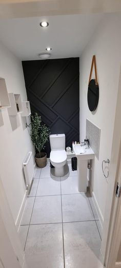 a white toilet sitting next to a sink in a bathroom under a black and white wall