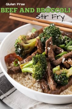 a white bowl filled with beef and broccoli on top of rice next to chopsticks