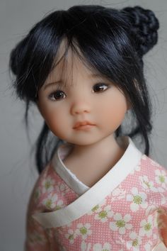 a doll with black hair wearing a pink and white kimono, looking at the camera