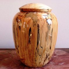 a large wooden urn sitting on top of a marble counter next to a white wall