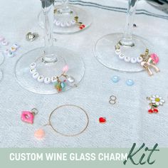 wine glasses with personalized charms on them are sitting on a tablecloth that says custom wine glass charm kit