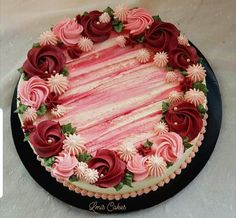 a cake with pink and white frosting flowers on it's side, sitting on a black plate