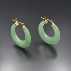 A vibrant vintage pair of green jade and 14 karat gold hoop earrings. Beautiful carved jade hoops are a covetable and easy jewelry staple and these are special ones, crafted of two crescent-shaped pieces of the loveliest medium green jadeite jade. Jade is a mineral known for its excellent toughness (resistance to breakage) due to its structure composed of interlocking small crystals. These earrings are secured by a 14k gold cap on either edge of the jade ring, linked by a hinged, slightly curved ear-wire that fastens in a U-shaped catch.   More details: 28.0mm front to back, 16.6mm front to back (inside of hoop,) 29.0mm top to bottom, 5.6mm thick Excellent condition 14k (stamped) 11.1 grams All purchases arrive in a gift box, wrapped with a ribbon. Jade Earrings Vintage, Jade Hoop Earrings, Earrings Gold Hoops, Green Pierced Hoop Earrings For Anniversary, Green Small Hoop Earrings Fine Jewelry, Green Jade Hoop Jewelry, Elegant Jade Hoop Earrings, Green Jade Hoop Earrings, Jade Jewellery