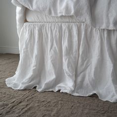 an unmade bed with white linens on top of it and a pillow under the covers