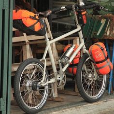 a bicycle parked in front of a building with orange life jackets on it's back