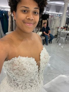 a woman in a wedding dress is smiling at the camera while another person sits behind her