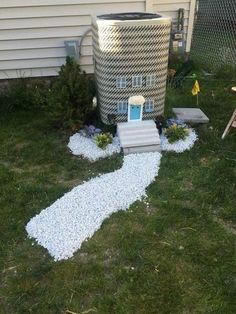 a house made out of rocks and gravel in front of a fenced in yard