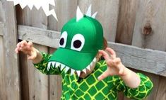 a young boy wearing a green dragon costume and holding his hands up to the side