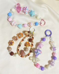 two bracelets with beads and charms are laying on a white sheet in the bed