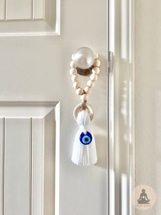 a door handle with an evil eye charm hanging from it's side, next to a white door