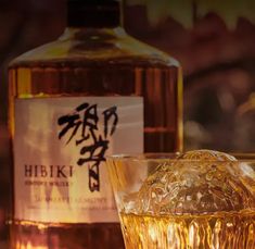 a bottle of hibiki whisky next to a glass filled with ice cubes