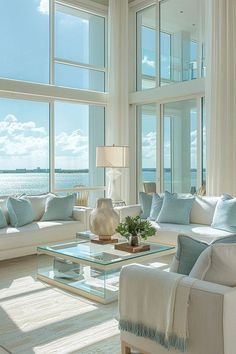 a living room filled with furniture and large windows overlooking the ocean on a sunny day