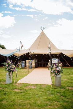 a large tent set up for a wedding with flowers in the vases on the grass