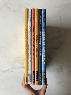 a hand holding four books in front of a white marble counter top with the title, how do you want to read this?