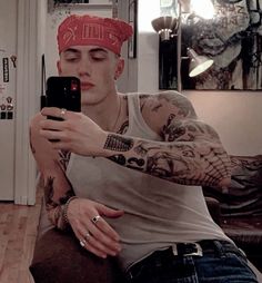 a man with tattoos on his arm taking a selfie