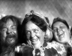 an old black and white photo of three women smiling at the camera, with one woman looking on