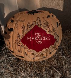 a carved pumpkin sitting on top of dry grass in front of a building with the word maraader's map painted on it