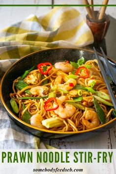 a bowl filled with noodles and shrimp on top of a table next to chopsticks