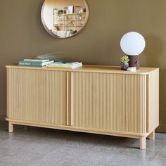 a sideboard with books and a mirror on the wall