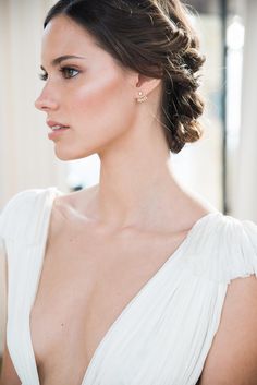 a woman in a white dress wearing gold earrings and a tiara with pearls on her head