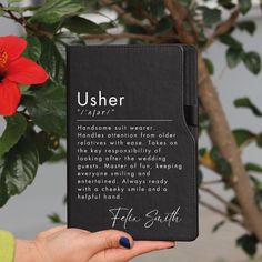 a person holding up a book with the words usher written on it and a flower in the background