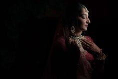 a woman in a red and gold bridal outfit with her hands on her chest