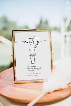 a sign that is on top of a wooden table next to a white and gold feather