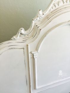 an antique white bed frame with carved details