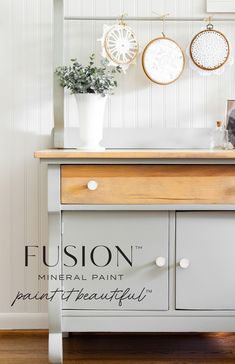 a white dresser with some plants and pictures on the wall above it that says fusion mineral paint