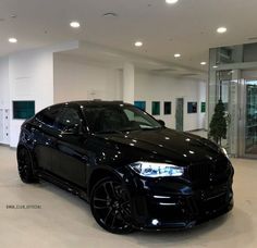 a black car is parked in the middle of a room with white walls and flooring