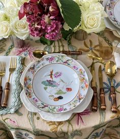 the table is set with flowers and gold utensils