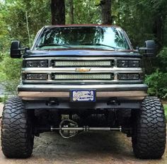 the front end of a pickup truck parked in a wooded area