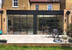 an outdoor patio with chairs and tables in front of a brick building that has glass doors