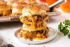 three cheeseburger sliders stacked on top of each other with parsley in the background