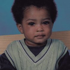 a young boy sitting in a chair wearing a sweater