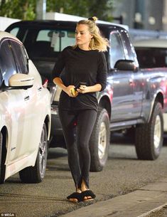 a woman is walking down the street with her hand in her pocket and wearing sandals