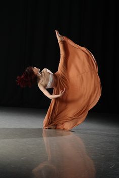 a woman in an orange dress is dancing