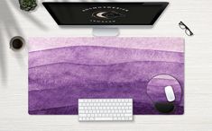 a computer mouse and keyboard sitting on top of a purple desk mat next to a monitor