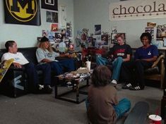 a group of people sitting on couches in a room with posters and skateboards