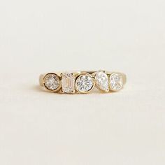 three stone ring in yellow gold with diamonds on each side and four smaller stones at the bottom