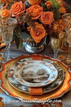 an elegant table setting with orange roses in the center and gold rimmed dishes on it